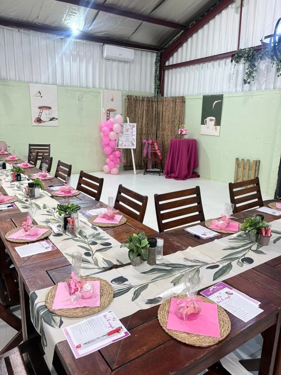 Baby shower dining setup with pink place settings, decorated table and dessert station