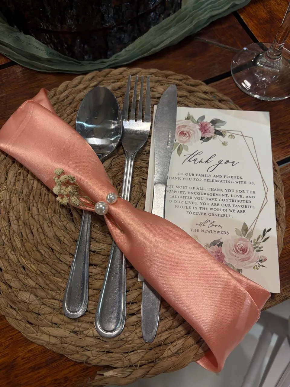 Wedding place setting with woven charger, cutlery and a thank-you card