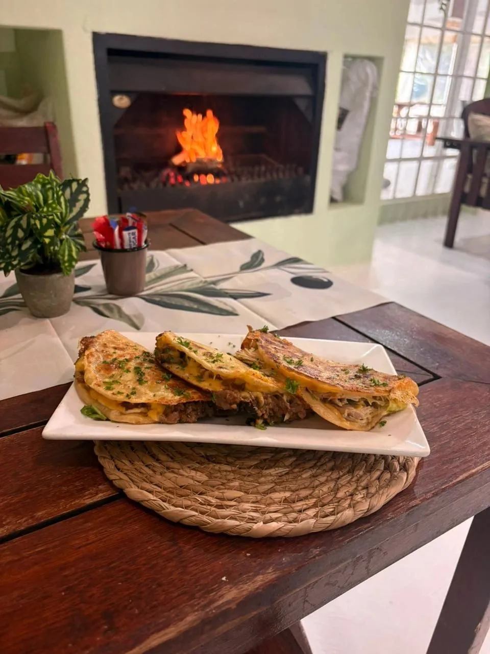 A plated meal on a woven trivet beside the restaurant fireplace