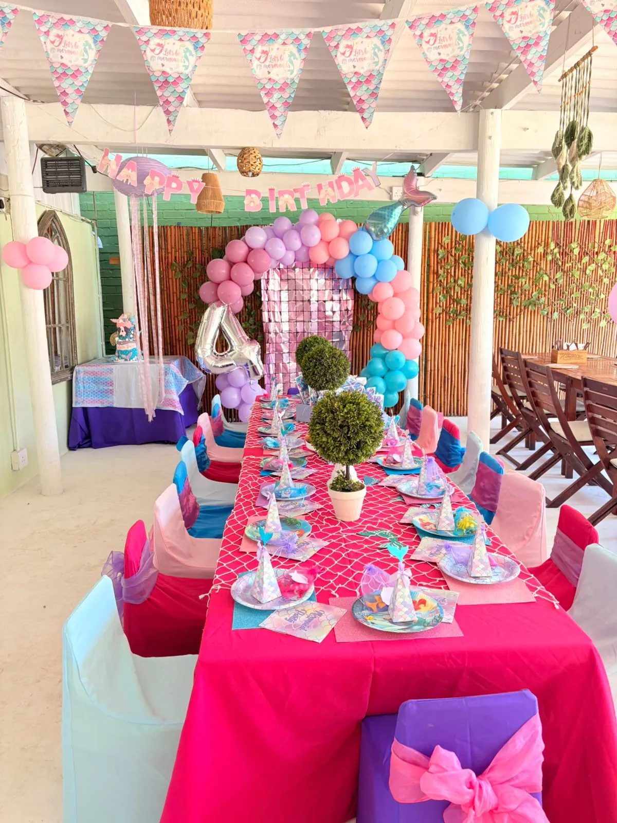 Colourful children's birthday party setup with decorated table and balloon arch