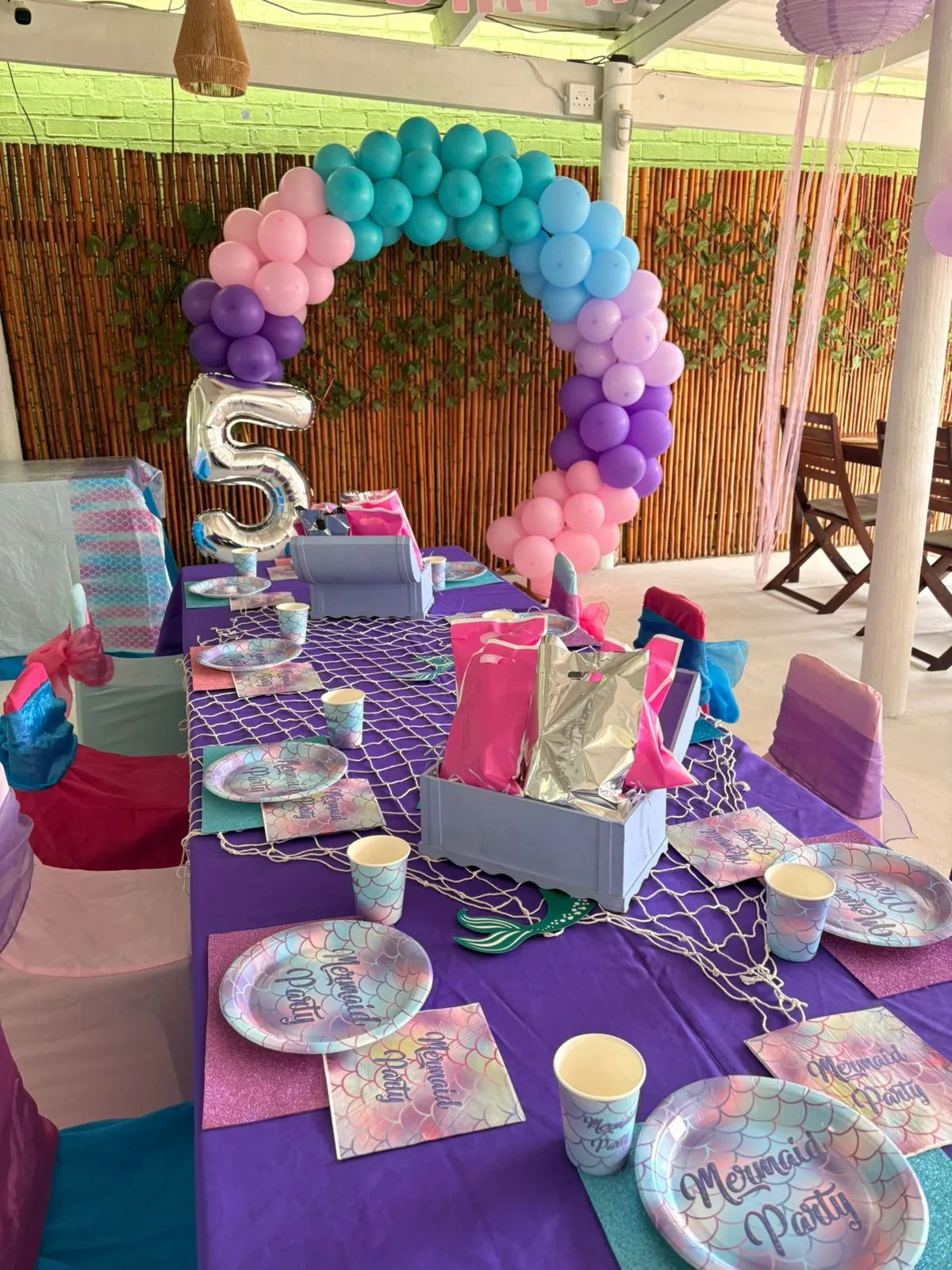 Colourful kids party table with balloon arch and place settings