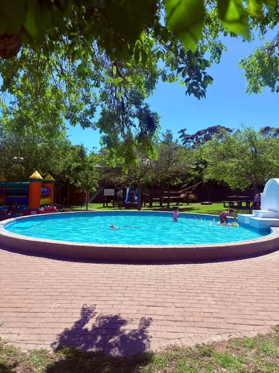 Outdoor pool and inflatable play area with children at Olive & Vine
