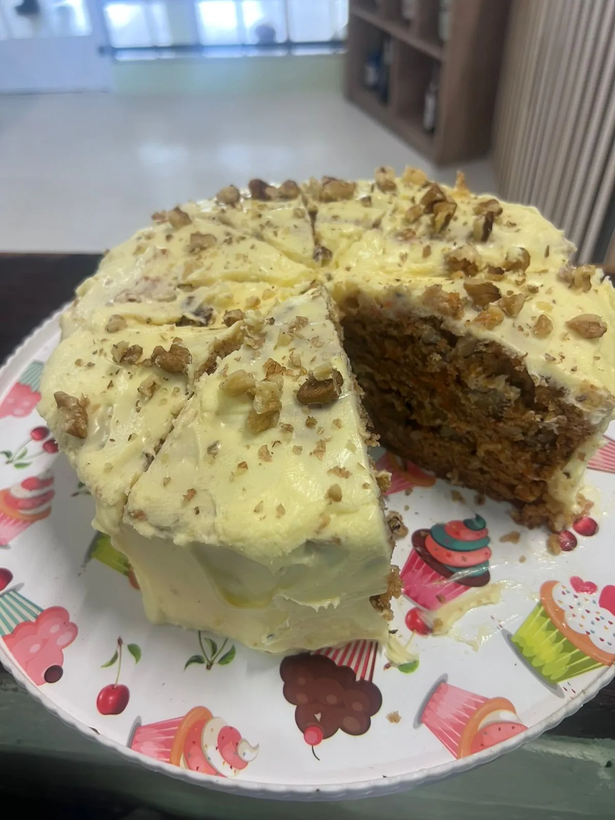 Slice of iced carrot cake topped with chopped nuts